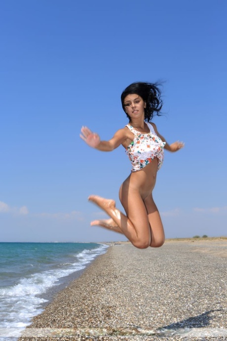 Teen solo girl Tanaia J strikes great nude poses on a towel at a rocky beach