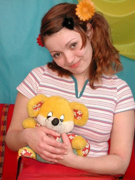 Young looking redhead holds a Teddy Bear before having sex with her boyfriend