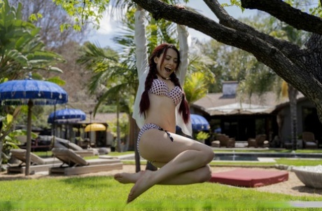 Young redhead Sabina Rouge swings from a branch before posing totally naked