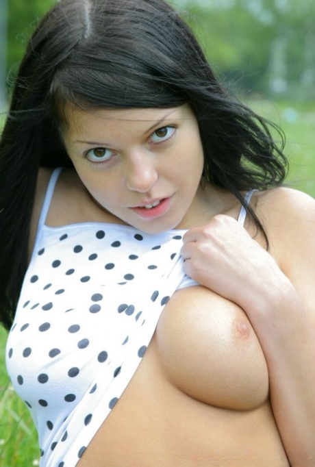 Young brunette fondles her full breasts amid trees near the water