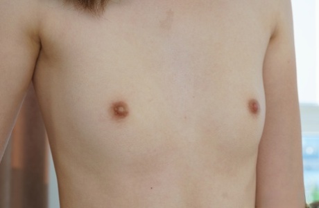 Skinny teen Ariel uncovers her flat chest as she gets totally naked on a sofa