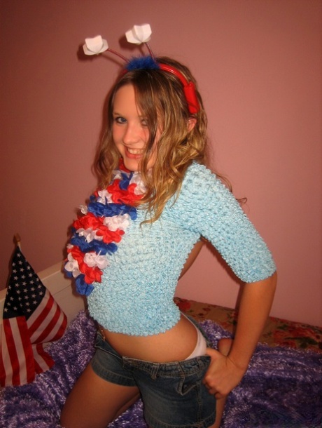 Cute teen holds an American flag while saluting after a finger fuck