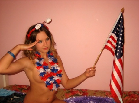 Cute teen holds an American flag while saluting after a finger fuck