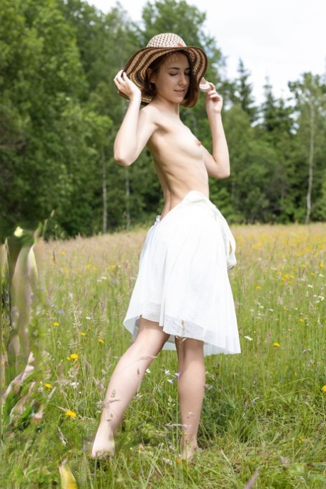 Teen amateur Ava bares her skinny body in a field while wearing a sun hat