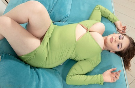 Thick beauty Molly Evans sets her giant boobs free of a dress on a sofa