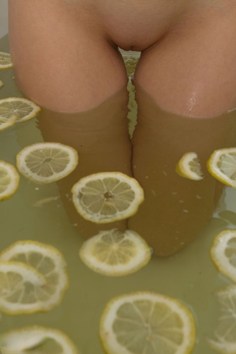 Cute blonde teen sinks her bald twat into a tub filled with lemon slices