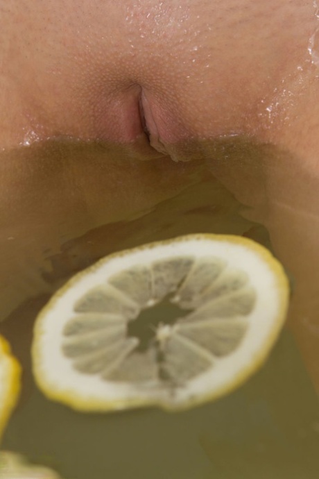 Cute blonde teen sinks her bald twat into a tub filled with lemon slices
