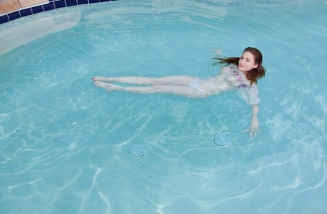 Busty redheaded teenage girlfriend Emily Archer takes a bath in the pool