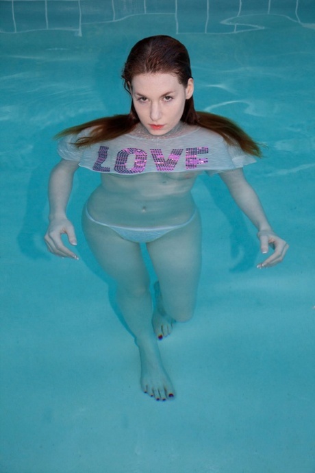 Busty redheaded teenage girlfriend Emily Archer takes a bath in the pool