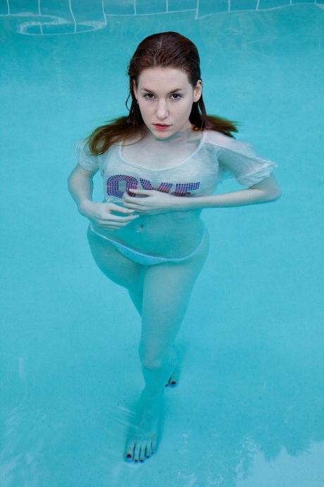 Busty redheaded teenage girlfriend Emily Archer takes a bath in the pool