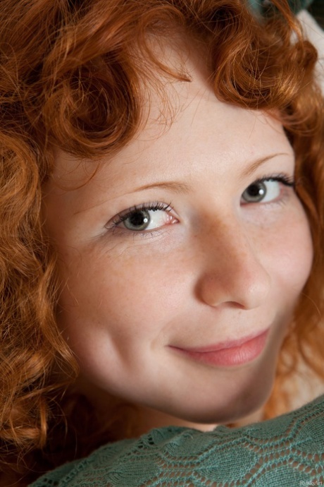 Curly-haired redhead Rochelle exposes her sexy body and poses on her bed