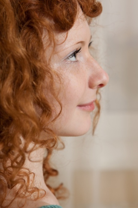 Curly-haired redhead Rochelle exposes her sexy body and poses on her bed