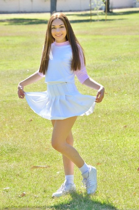 Brunette cutie Kelly reveals her tiny tits and fingers her snatch in the park