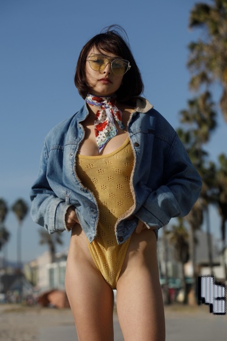 Adorable teen Basil Navas poses on the beach in yellow see-through bodysuit