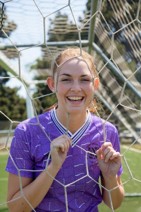Sporty redhead teen Bailey Rayne flashes her tight ass on the soccer field
