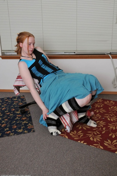 Redheaded babe Sandy shows her small teen tits while undressing