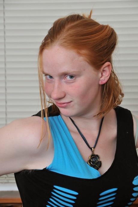 Redheaded babe Sandy shows her small teen tits while undressing