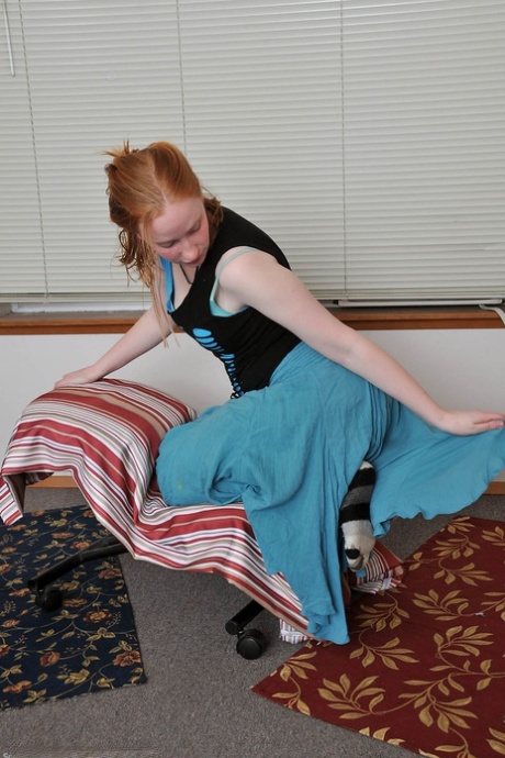 Redheaded babe Sandy shows her small teen tits while undressing