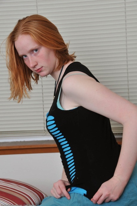 Redheaded babe Sandy shows her small teen tits while undressing