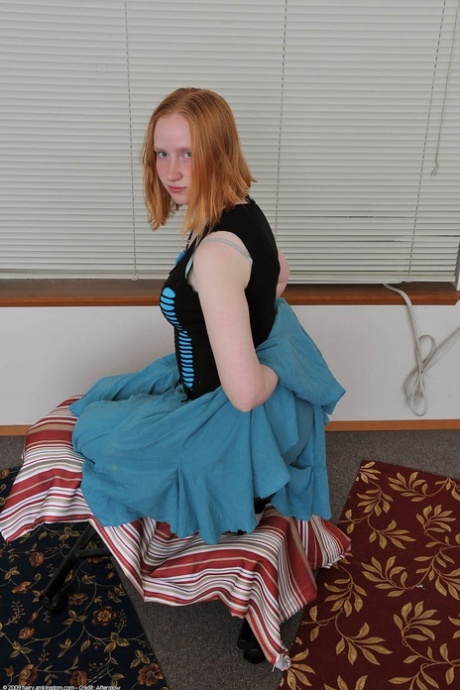 Redheaded babe Sandy shows her small teen tits while undressing