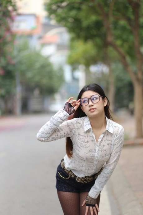Nerdy Asian babe Natalia posing in her white blouse and denim shorts outside