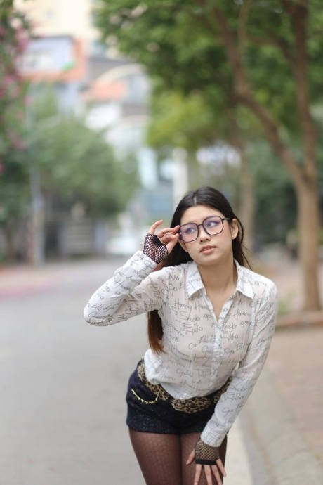 Nerdy Asian babe Natalia posing in her white blouse and denim shorts outside