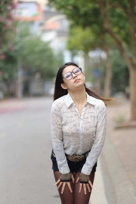 Nerdy Asian babe Natalia posing in her white blouse and denim shorts outside