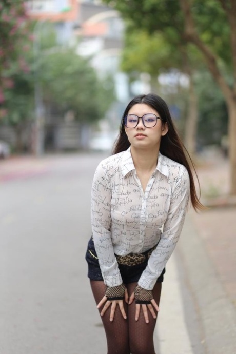 Nerdy Asian babe Natalia posing in her white blouse and denim shorts outside