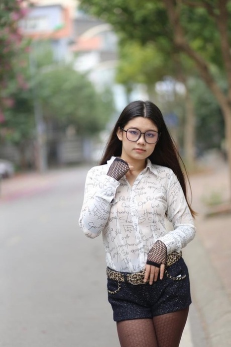 Nerdy Asian babe Natalia posing in her white blouse and denim shorts outside