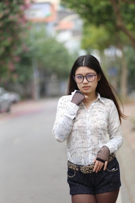 Nerdy Asian babe Natalia posing in her white blouse and denim shorts outside