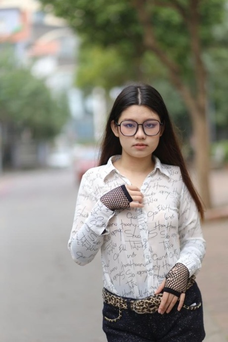 Nerdy Asian babe Natalia posing in her white blouse and denim shorts outside