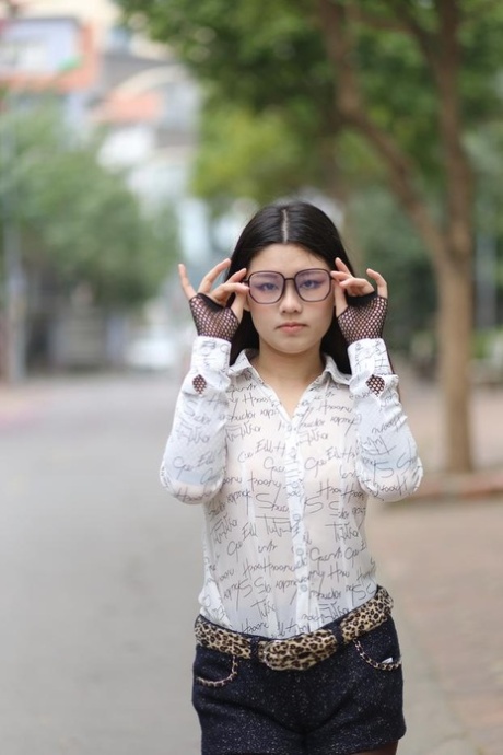 Nerdy Asian babe Natalia posing in her white blouse and denim shorts outside