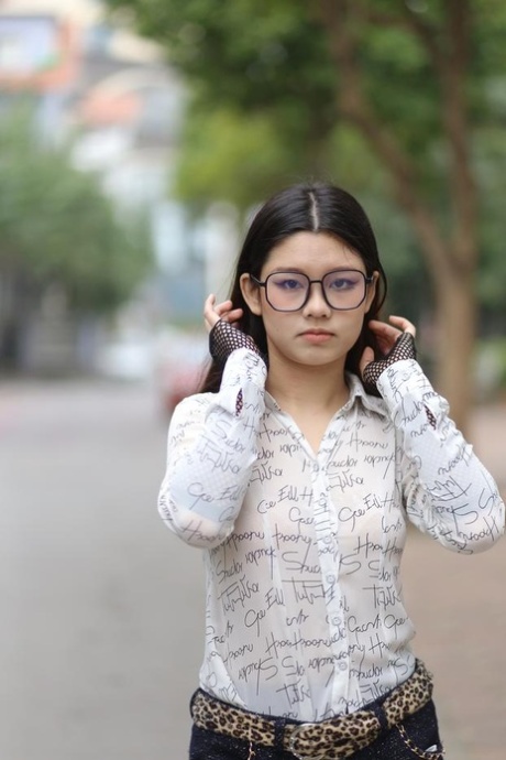 Nerdy Asian babe Natalia posing in her white blouse and denim shorts outside