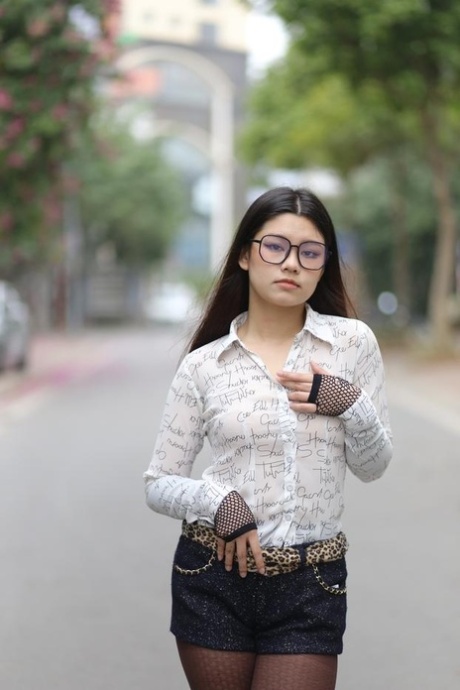 Nerdy Asian babe Natalia posing in her white blouse and denim shorts outside