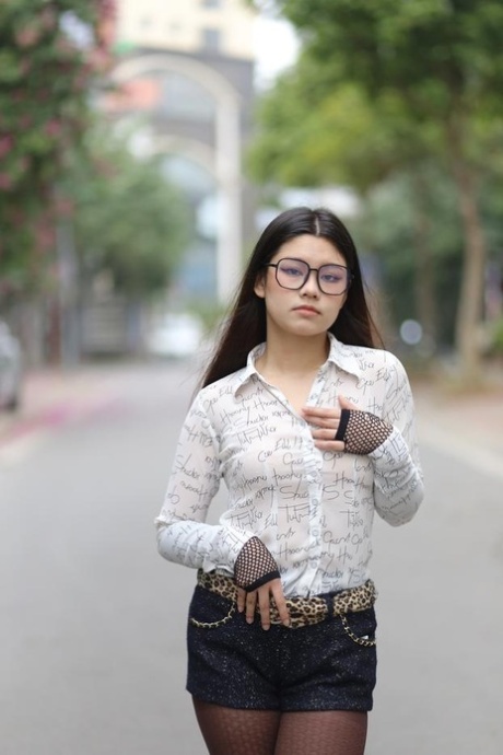 Nerdy Asian babe Natalia posing in her white blouse and denim shorts outside