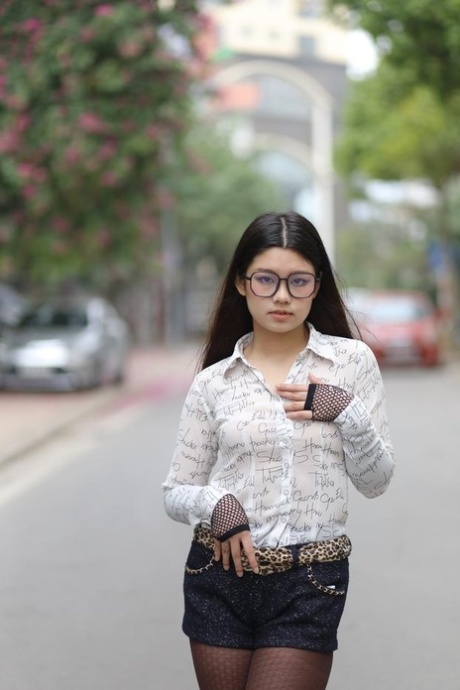 Nerdy Asian babe Natalia posing in her white blouse and denim shorts outside
